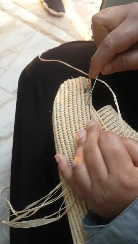 Artesano tejiendo a mano una sandalia de rafia, ejemplo de pieza natural artesanal